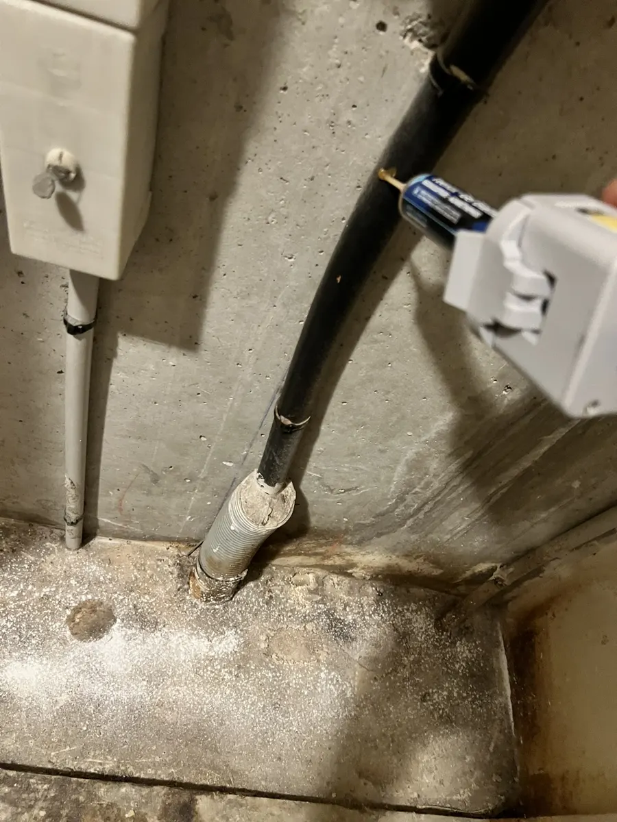 Traces d'humidité au pied d'une colonne technique dans un appartement infesté de cafards