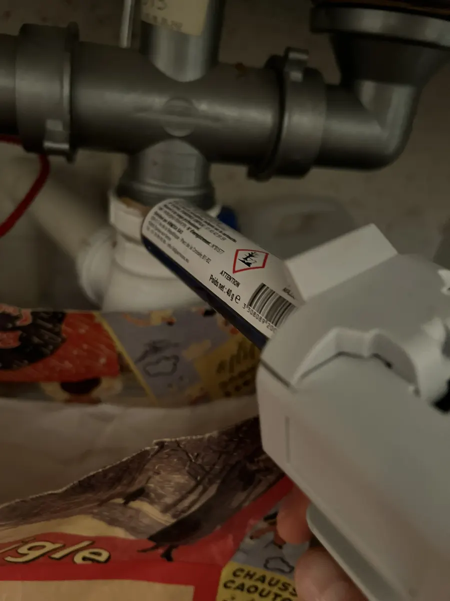 Application d'insecticide au pied de canalisations dans un placard de rangement