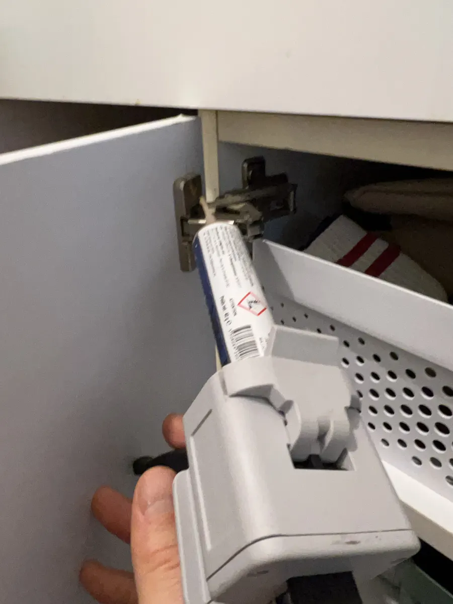 Application de gel anti-blattes dans la charnière d'un meuble de cuisine lors du 2e passage en copropriété