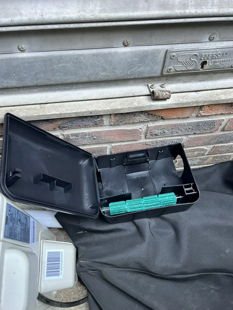 Bloc rodenticide fixé dans un poste d'appâtage sécurisé le long de la façade d'un immeuble